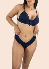 Woman wearing a navy blue bikini set on a beige background