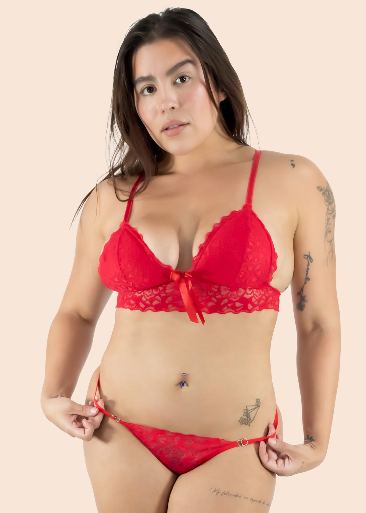 Woman wearing a red lace bra and panties set against a beige background
