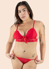 Woman wearing a red lace bra and panties set against a beige background