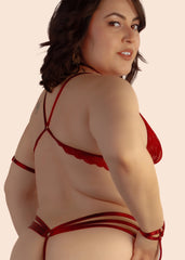 Woman wearing a red strappy top and bottom on a beige background