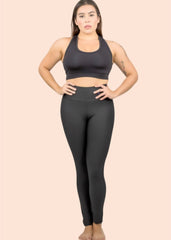 Woman wearing a black sports bra and leggings on a beige background