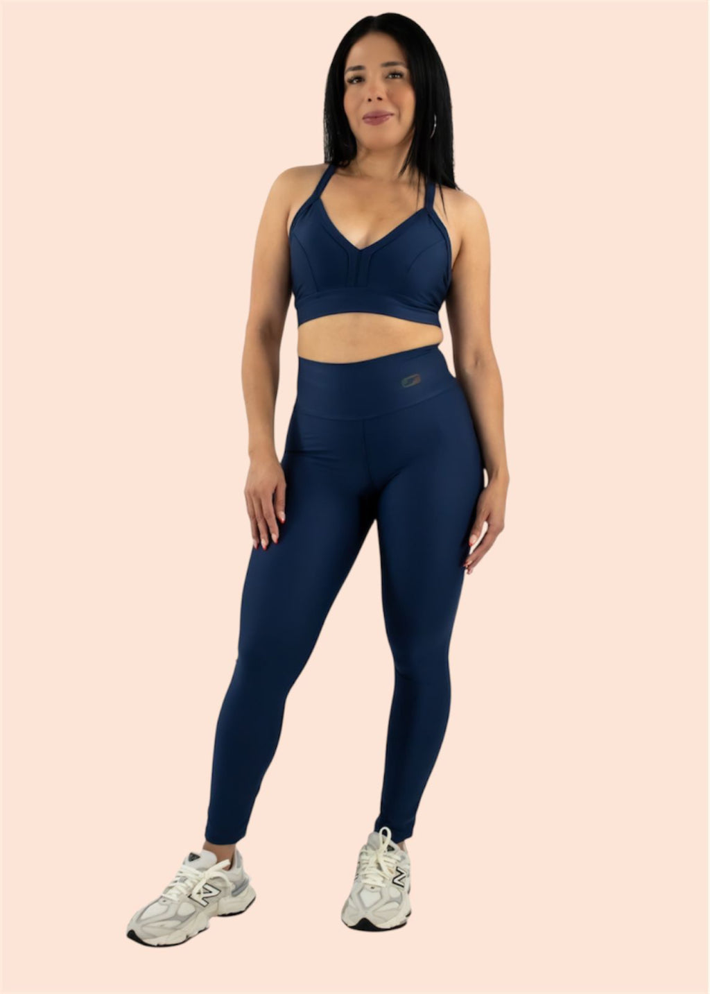 Woman wearing a navy athletic outfit on a light pink background
