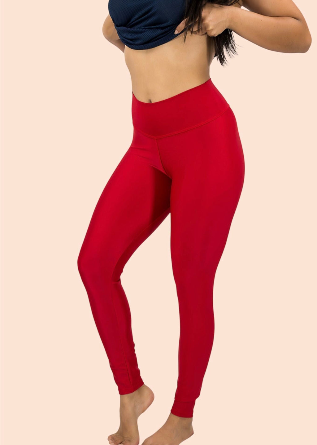 Person wearing red leggings and a navy top on a beige background