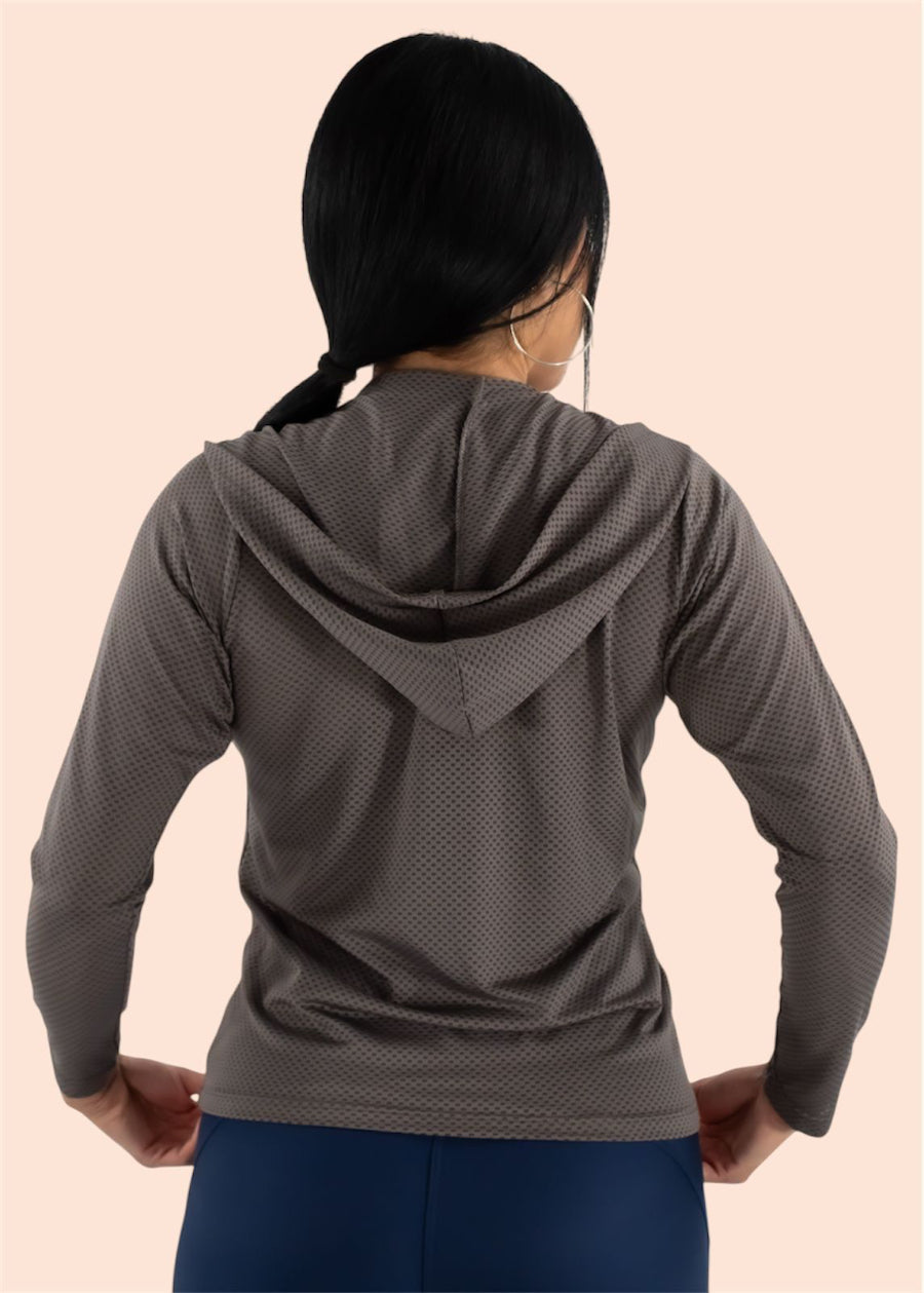 Person wearing a gray hooded sweatshirt on a beige background