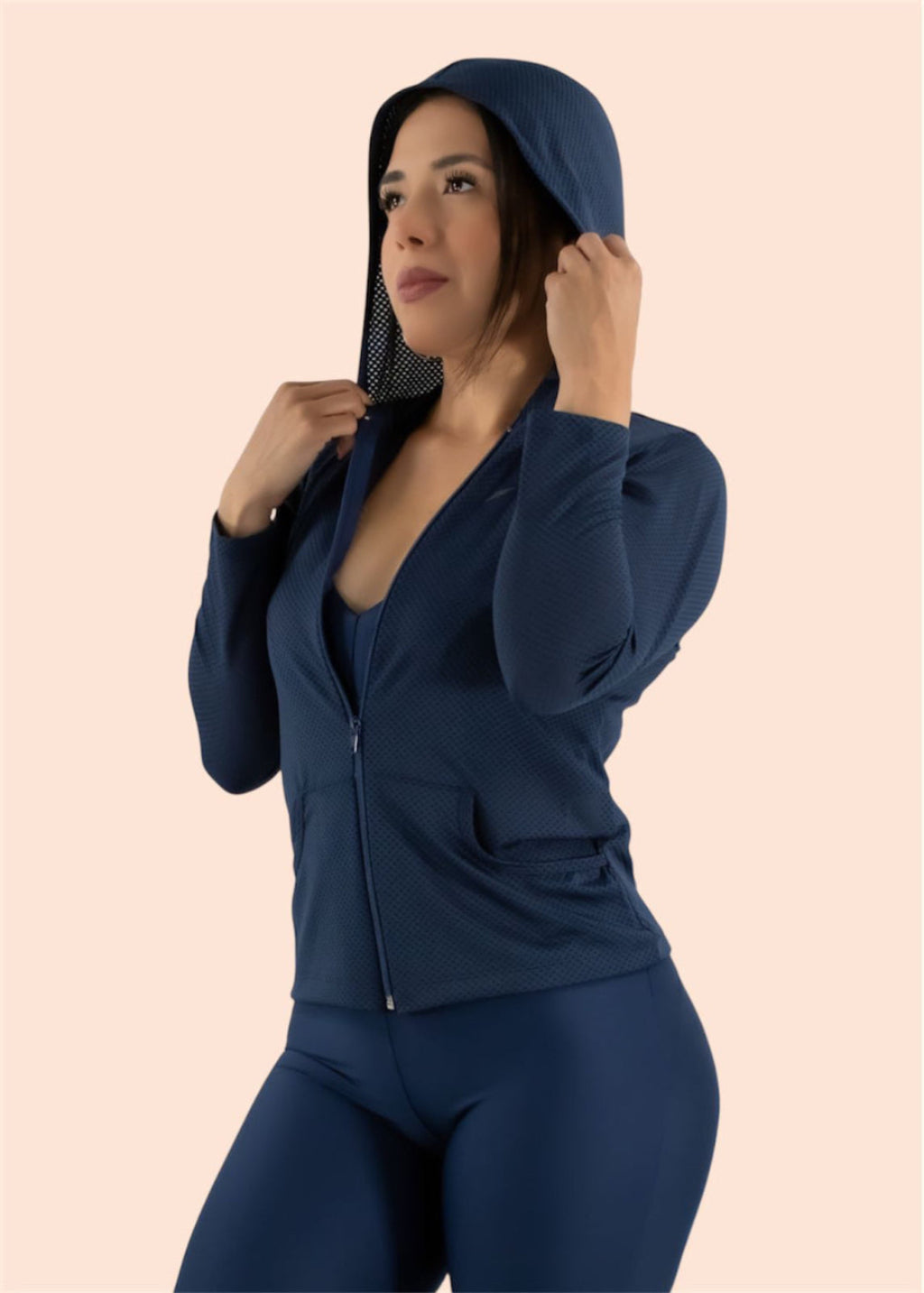 Woman wearing a navy blue athletic outfit on a beige background