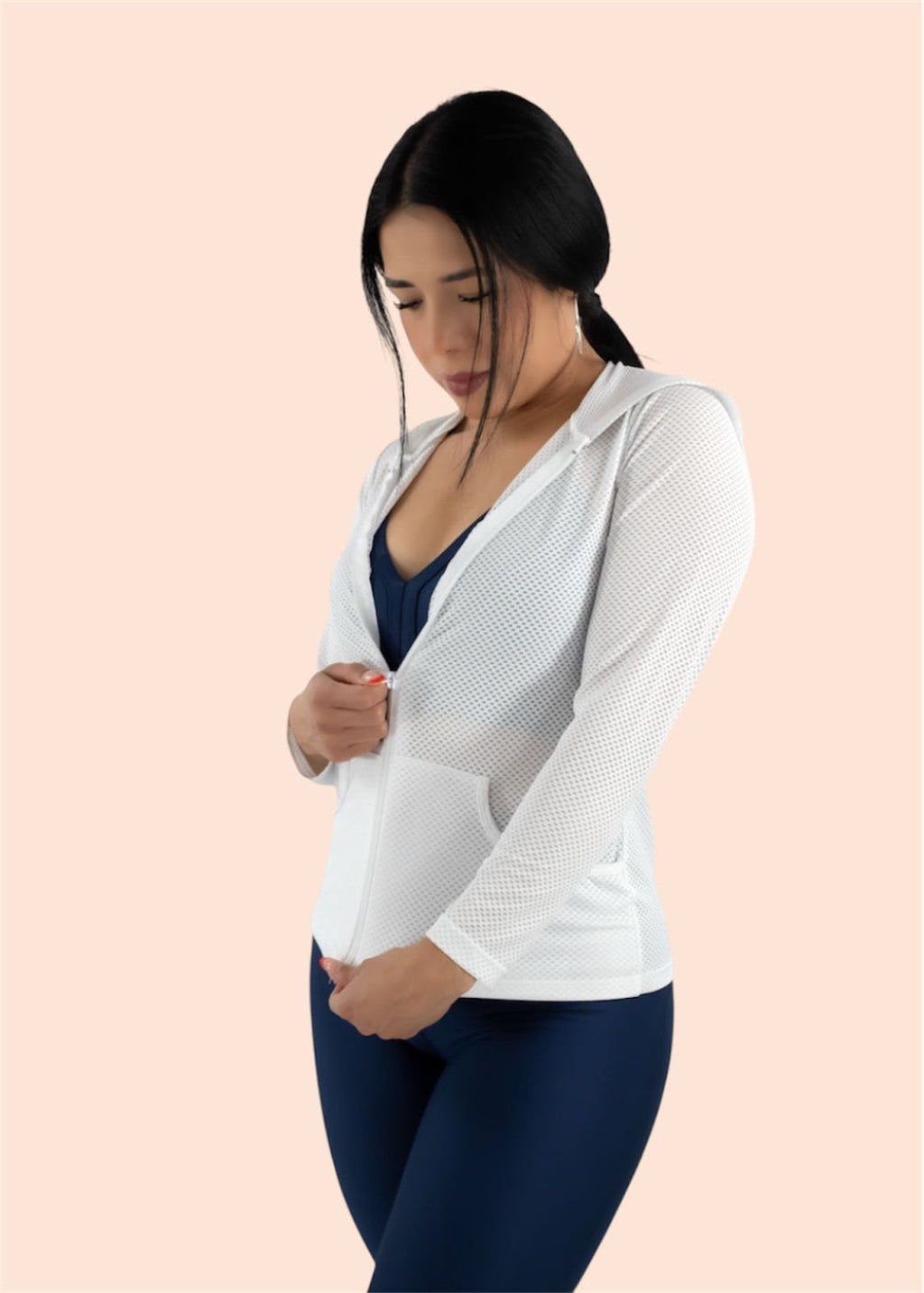 Woman wearing a white cardigan over a navy top on a beige background