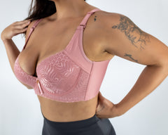Person wearing a pink lace sports bra and black leggings on a white background
