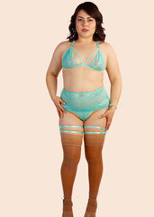 Woman wearing a turquoise lingerie set on a beige background