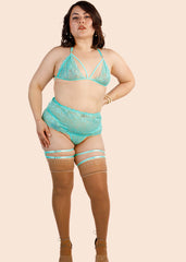 Woman wearing teal lace lingerie set on a beige background