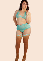 Woman wearing teal lingerie set with garter belt on a beige background