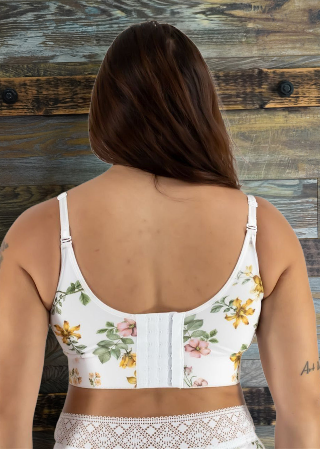 Woman wearing a floral-patterned crop top against a wooden wall.